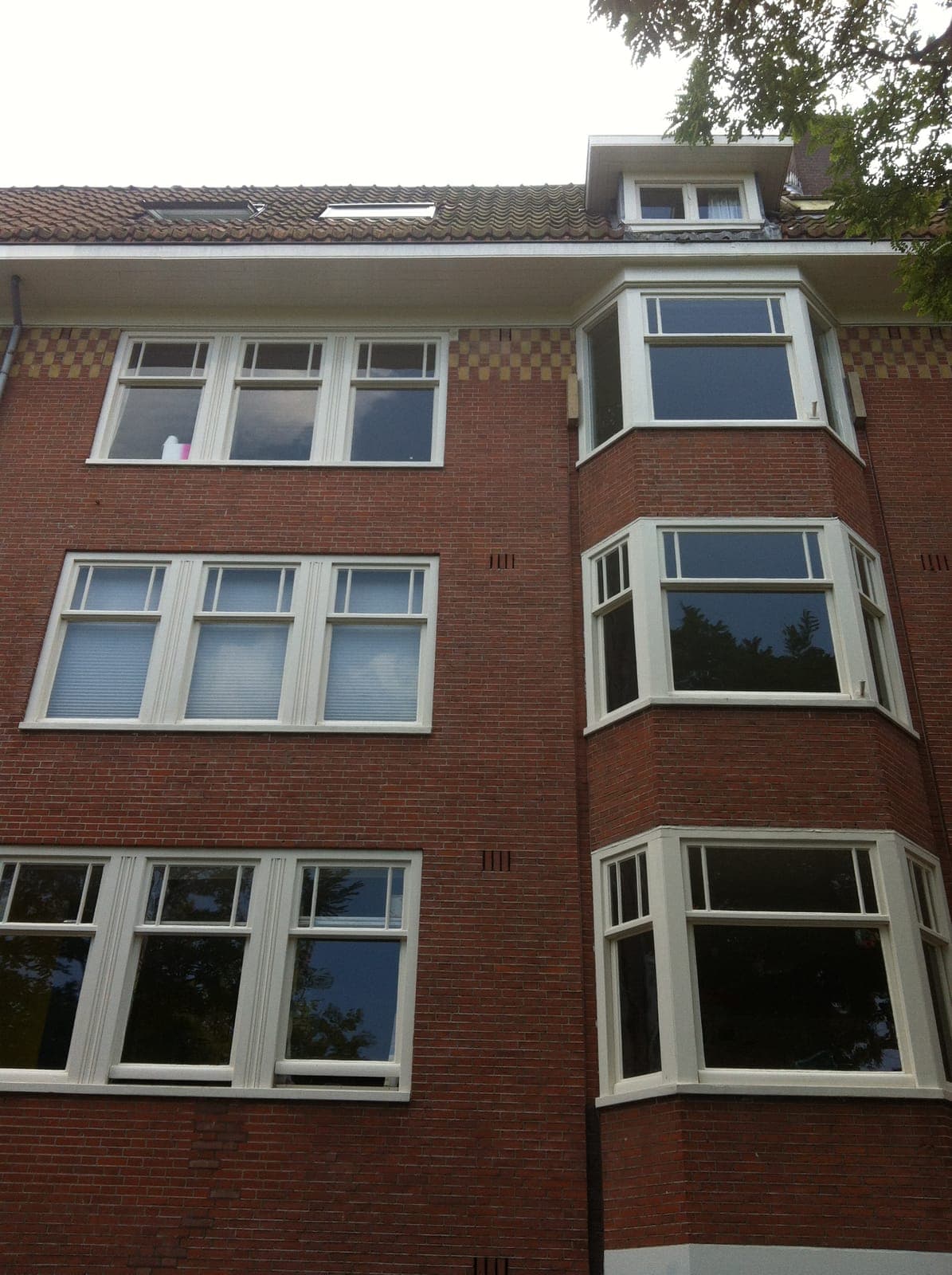 Jaren-30 gevel met erkers en witte schuiframen na onderhoud